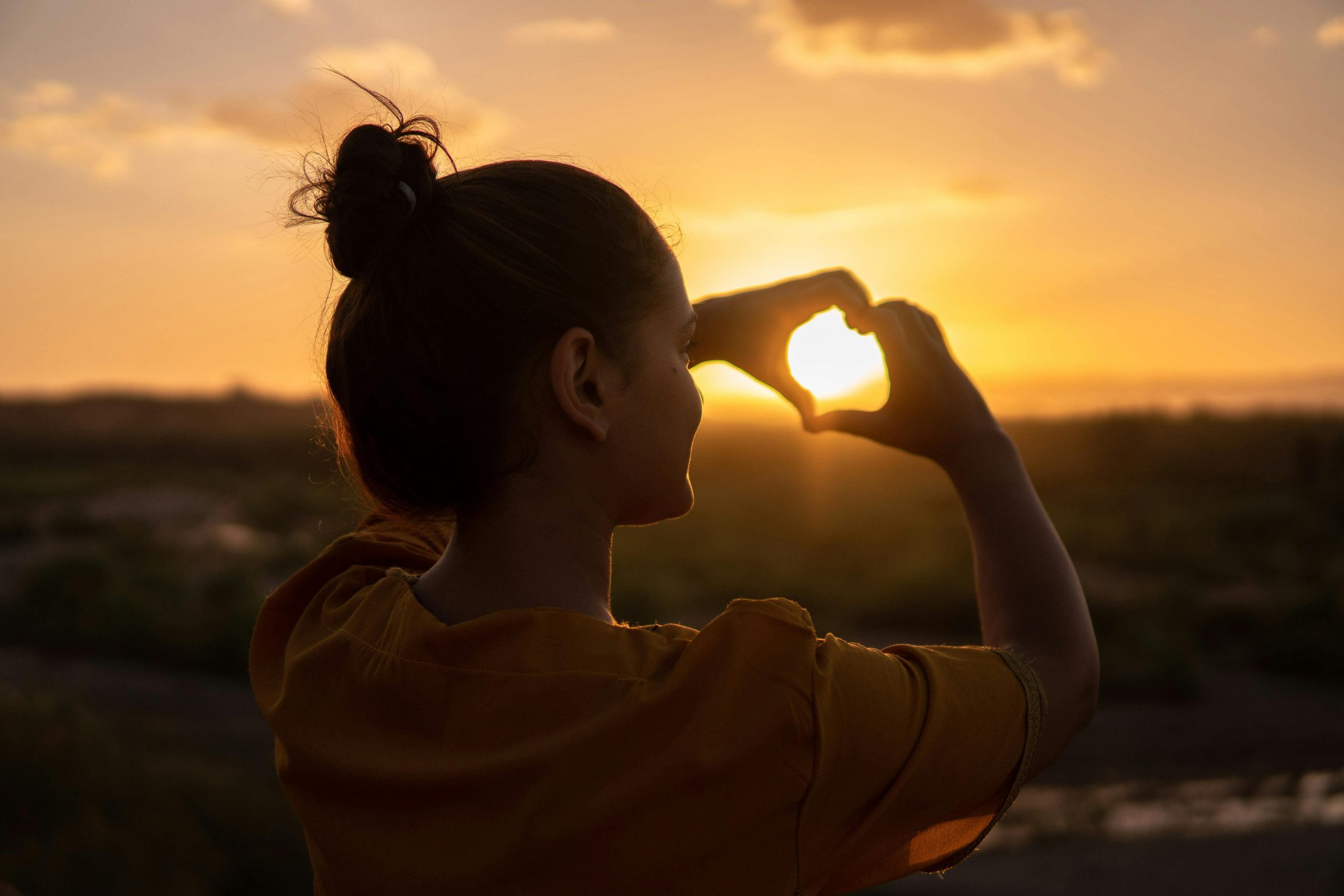 Chica enmarcando el sol